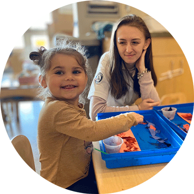 A teacher and a student pose in a classroom for a photo