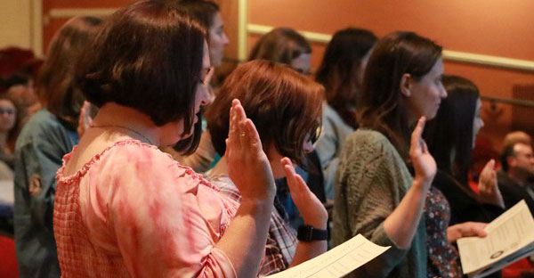 Photo of individuals in a concert hall reading a pledge