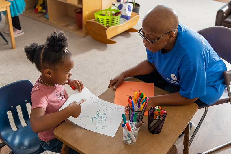 child at table with adult helping with colors and turning pages