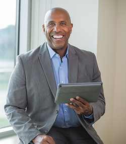 man sitting on a desk reading a tablet