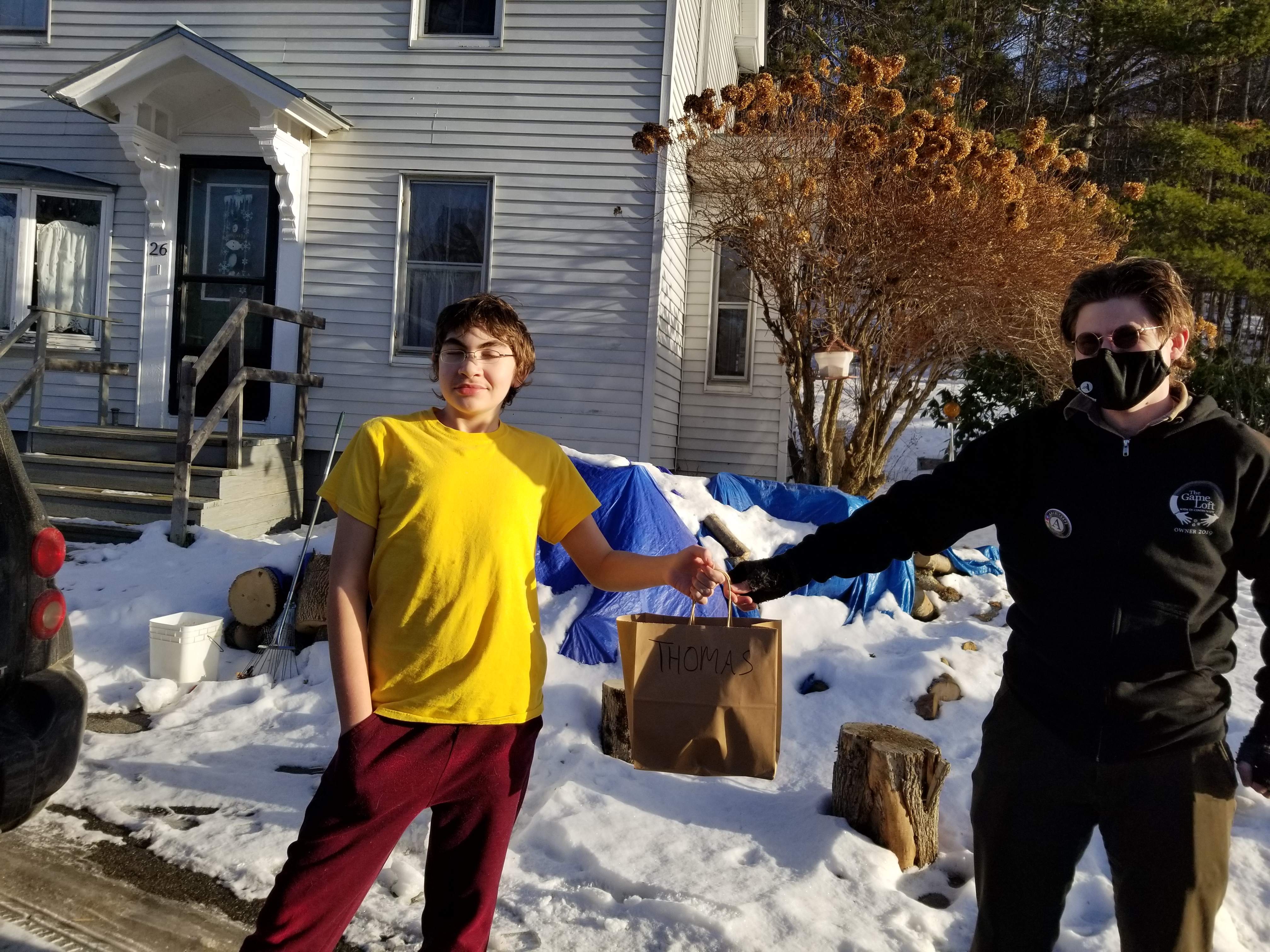 Child receives a bag of goods from adult at a social distance