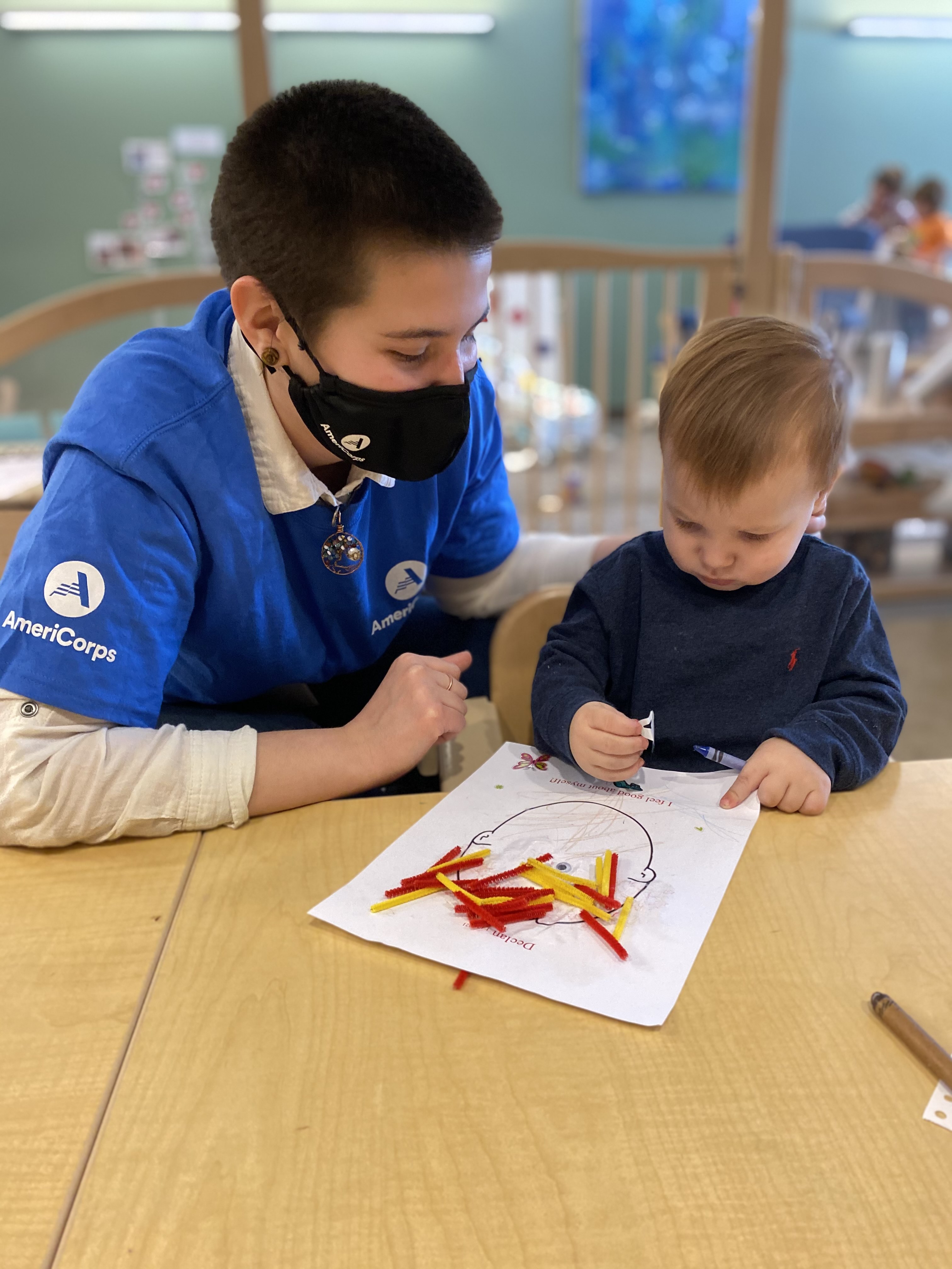 Teacher coloring with a student inside a classroom