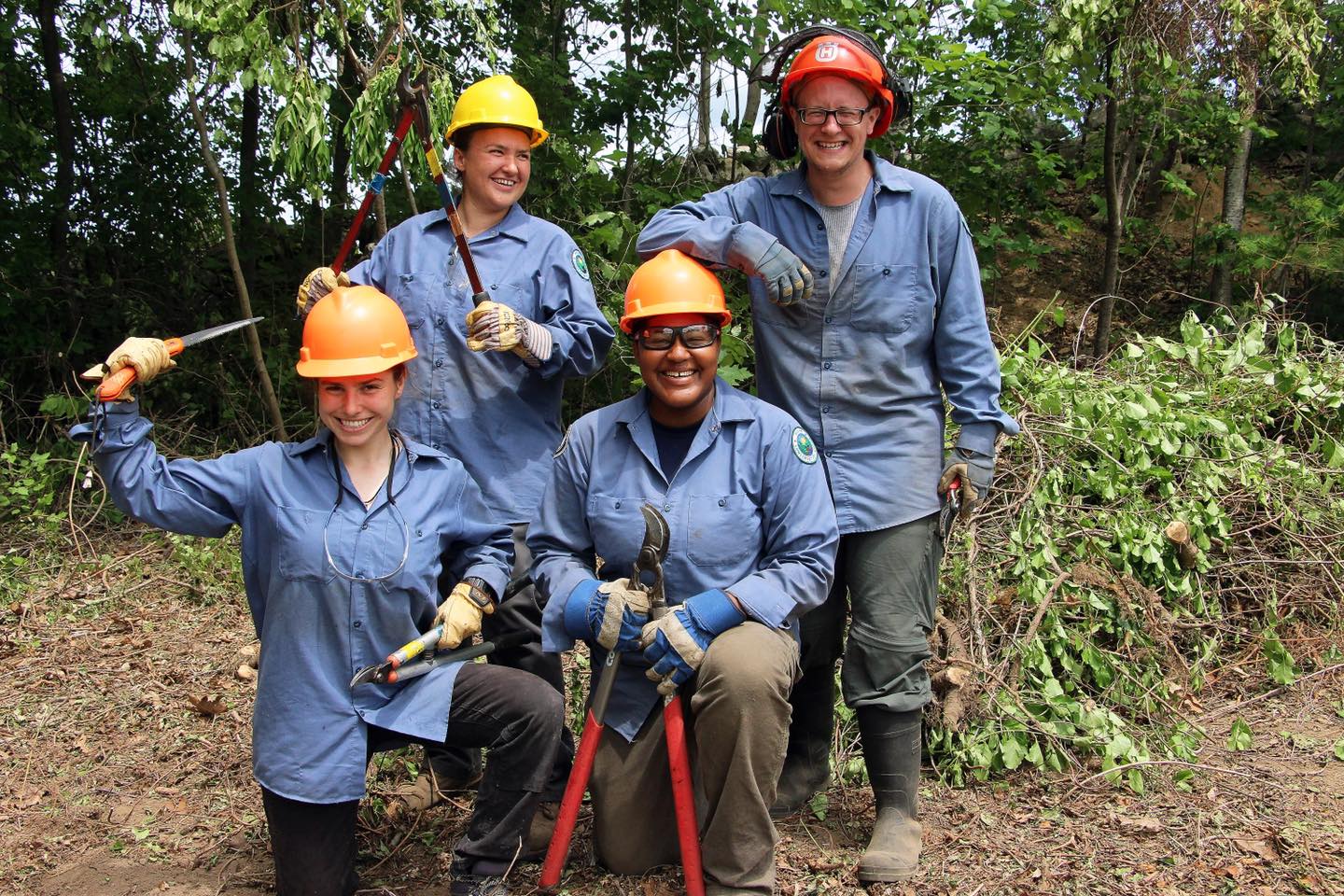 Photo of a group of people in a wooded area posing for a photo in trail maintenance gear