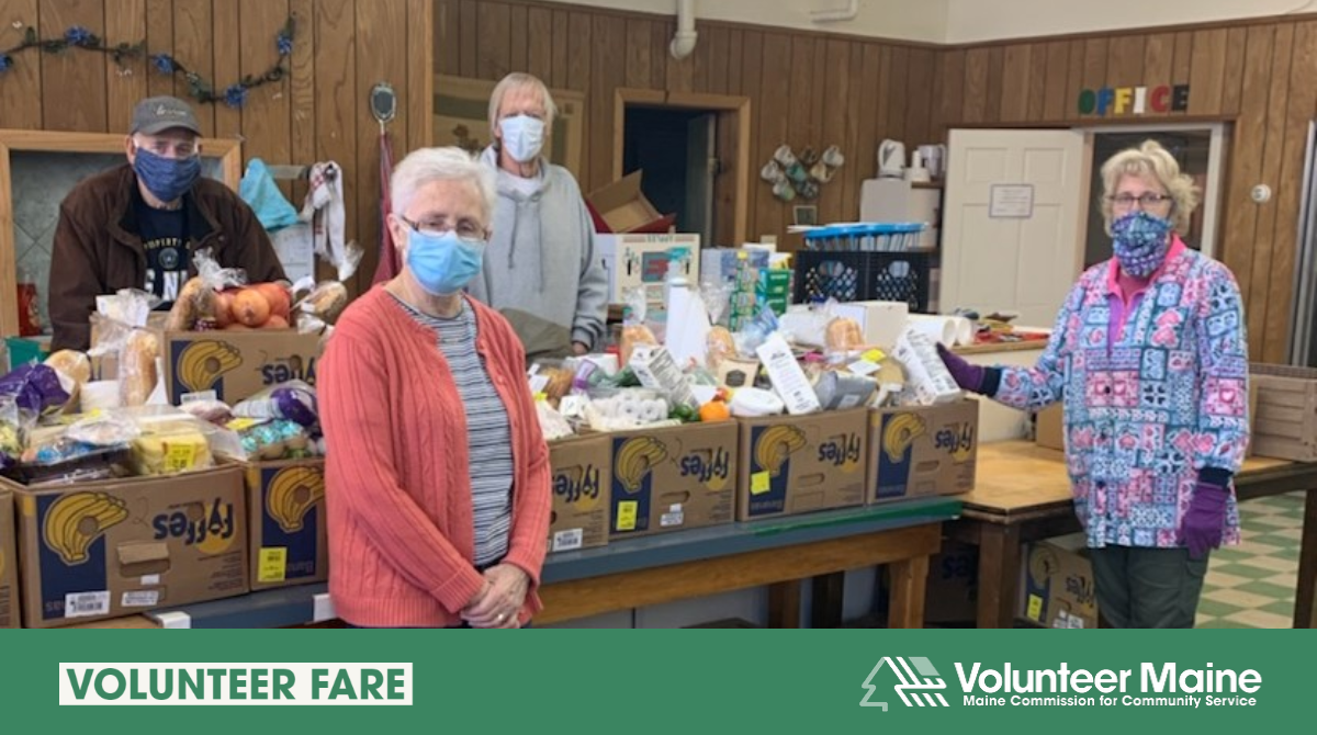 Photo of four individuals standing by a table full of food donations