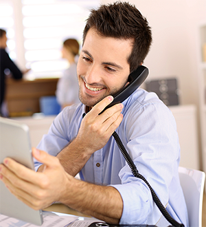 man seated looking at laptop and on phone